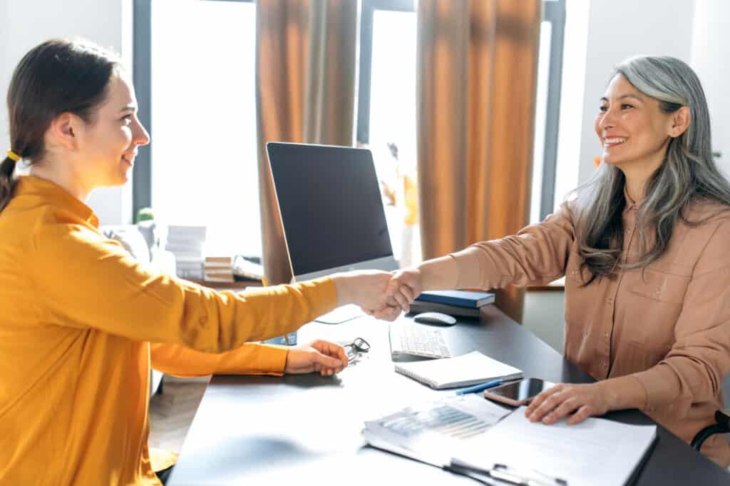 asian woman business woman office shakes hands smiles